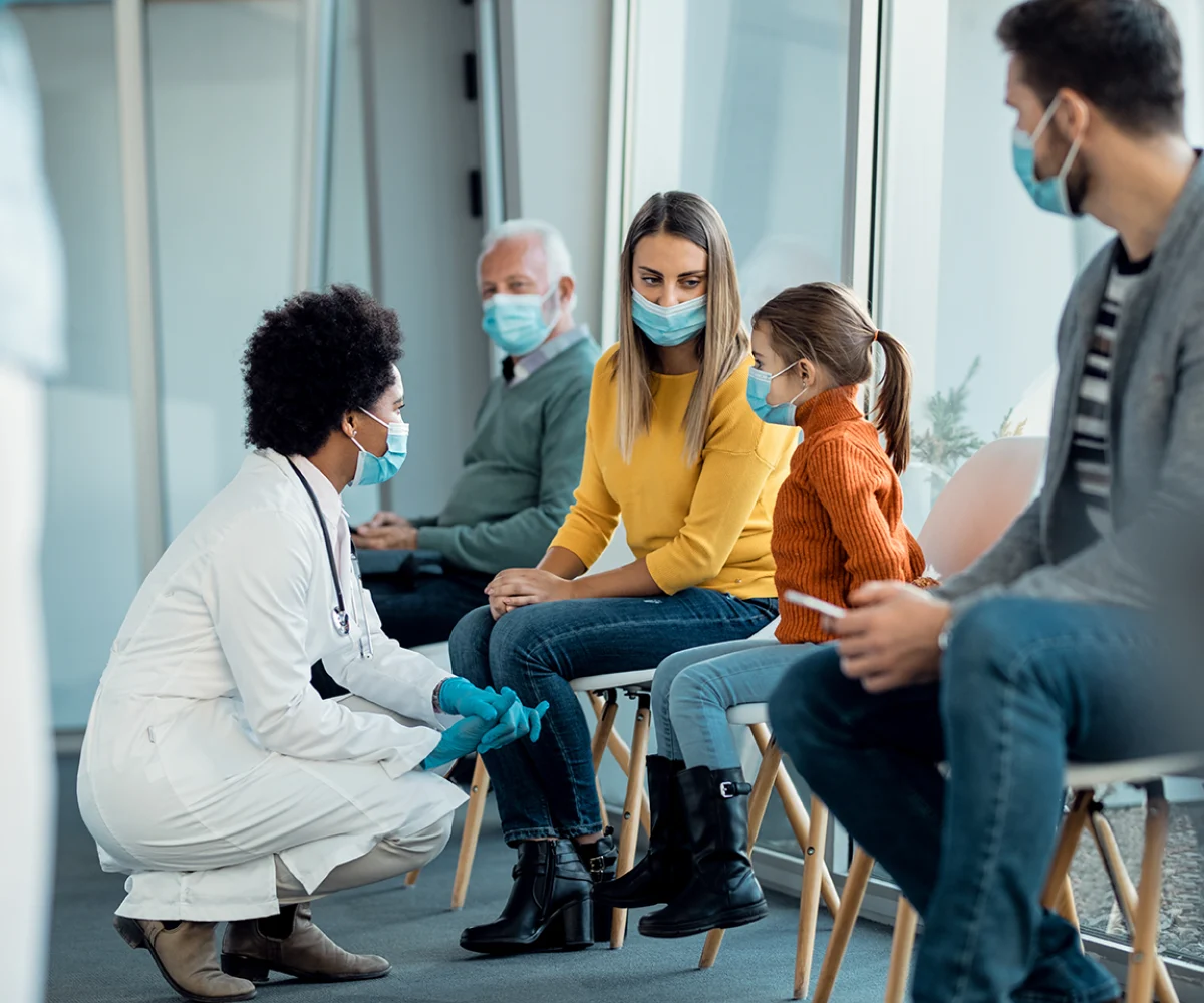 Medico che parla con una bambina e sua mamma